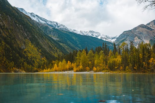 Idyllic mountain lake reflecting vibrant autumn trees and snow-capped peaks.