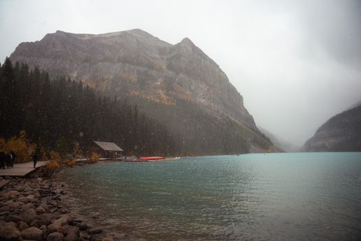 Serene landscape of Lake Louise with misty mountains and autumn foliage.