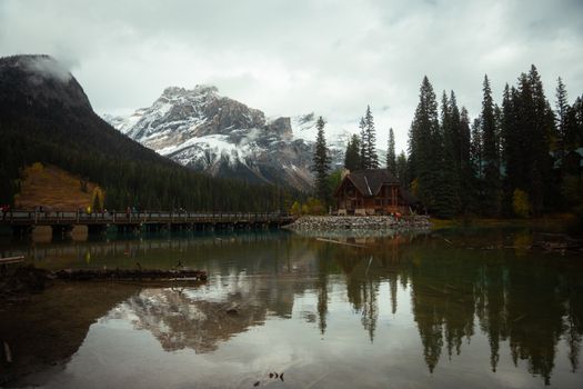 A picturesque mountain lodge near a serene lake with snow-capped peaks and lush forests.