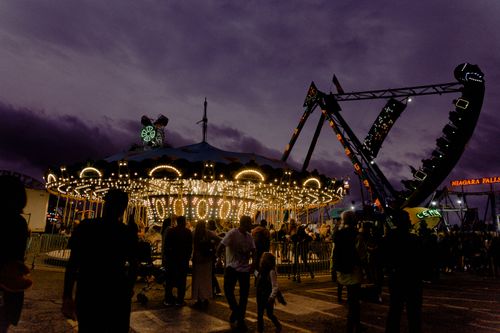 Free Illuminated carousel and thrill rides at an amusement park during twilight, capturing the essence of excitement and fun. Stock Photo