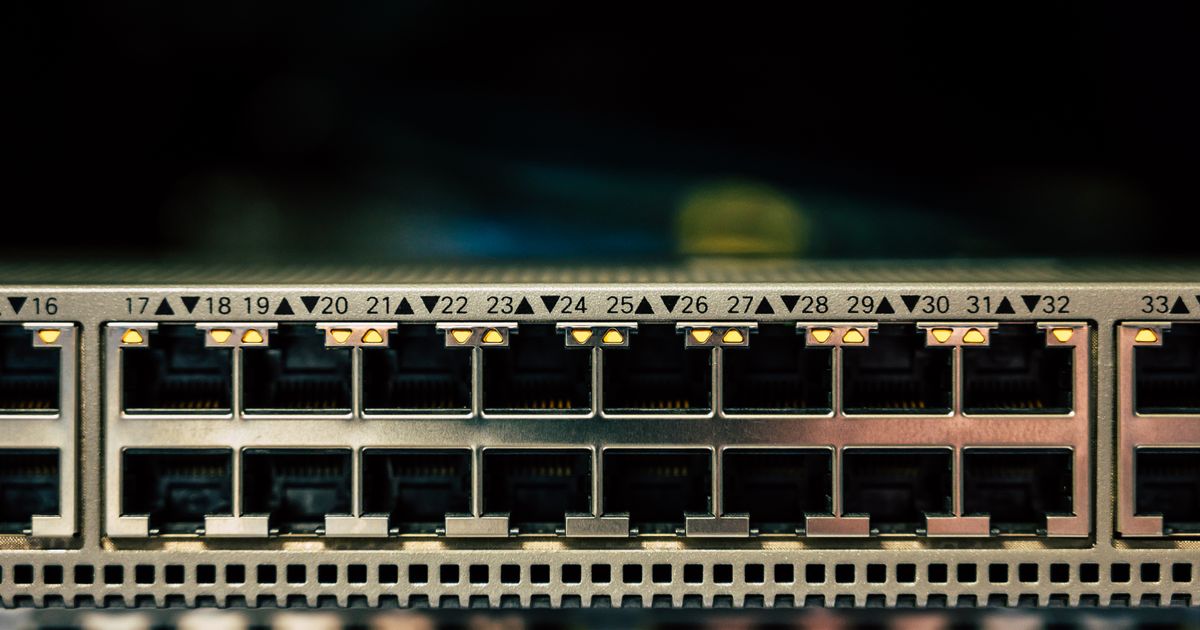 Gros plan sur les ports réseau d'un switch, voyants allumés, dans une baie informatique.