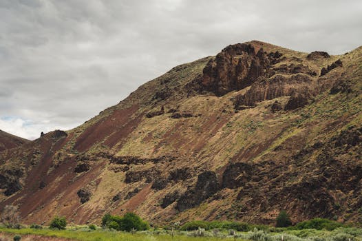 在多云的天空下，岩石山坡和沙漠景观呈现出雄伟的景色