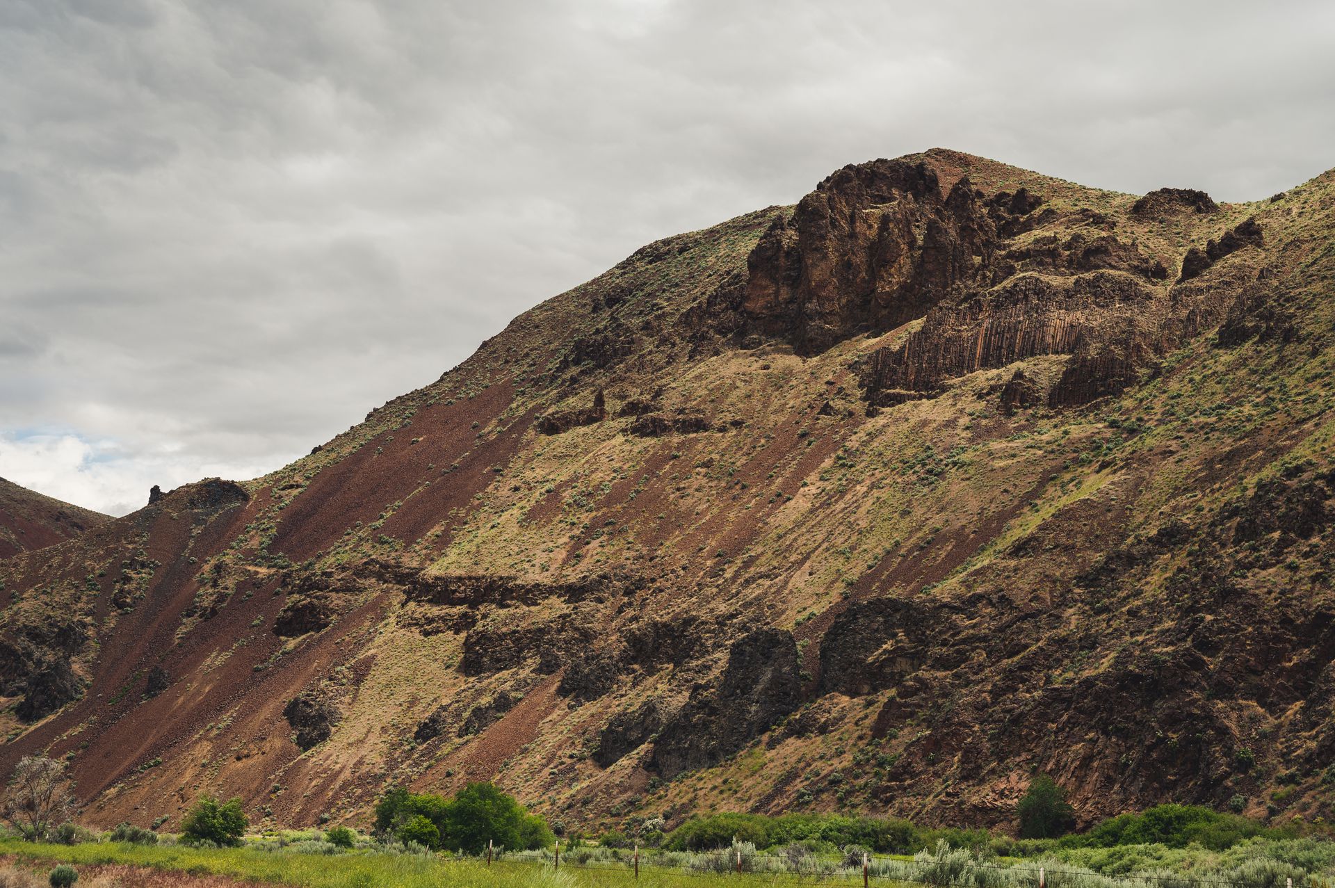 Majestic view of rocky hillside and desert landscape under a cloudy sky.