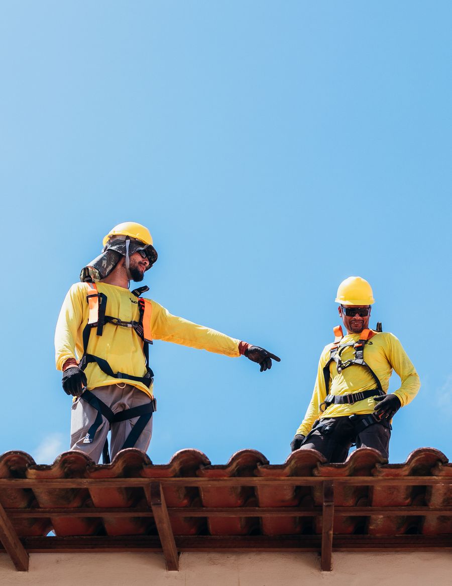 Two Copperline roofers discussing a project under a clear sky
