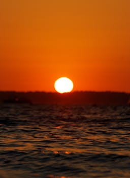 雄伟的日落映照在海面上，生动的橙色色调与闪烁的倒影交相辉映