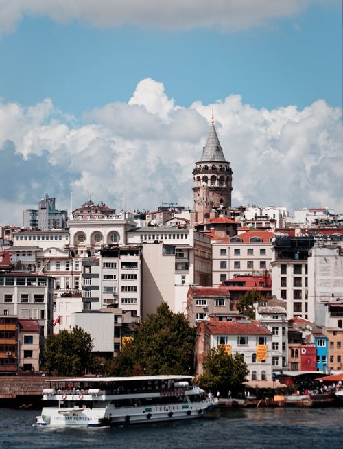 Free Galata Tower rising above the urban landscape of Istanbul with boats on the river. Stock Photo