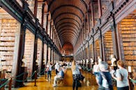 参观者在一所标志性大学的宏伟图书馆走廊中探索，那里有高耸的书架