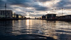 日落时分，都柏林河畔的天际线倒映在水中，景色美丽