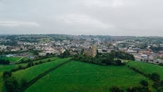 在多云的天空下，鸟瞰图捕捉到了广阔的绿色景观、迷人的城镇和历史建筑
