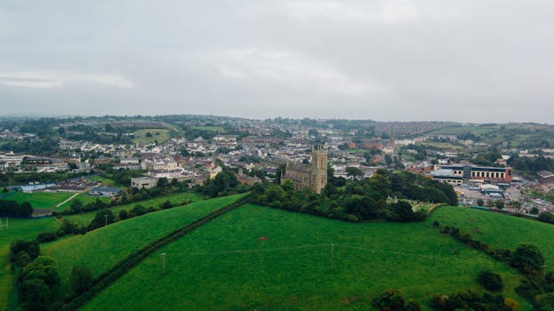 在多云的天空下，鸟瞰图捕捉到了广阔的绿色景观、迷人的城镇和历史建筑