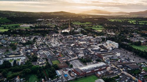 Free Breathtaking aerial view of a quaint town surrounded by lush greenery during a serene sunrise. Stock Photo