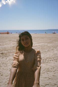 A woman in a dress enjoying a sunny day on the beach, capturing tranquility.