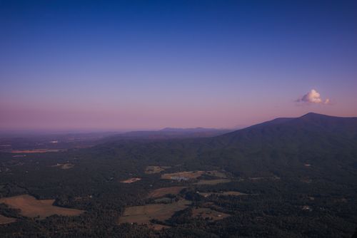 Free Scenic aerial view of rolling hills and mountains under a vibrant dusk sky. Stock Photo