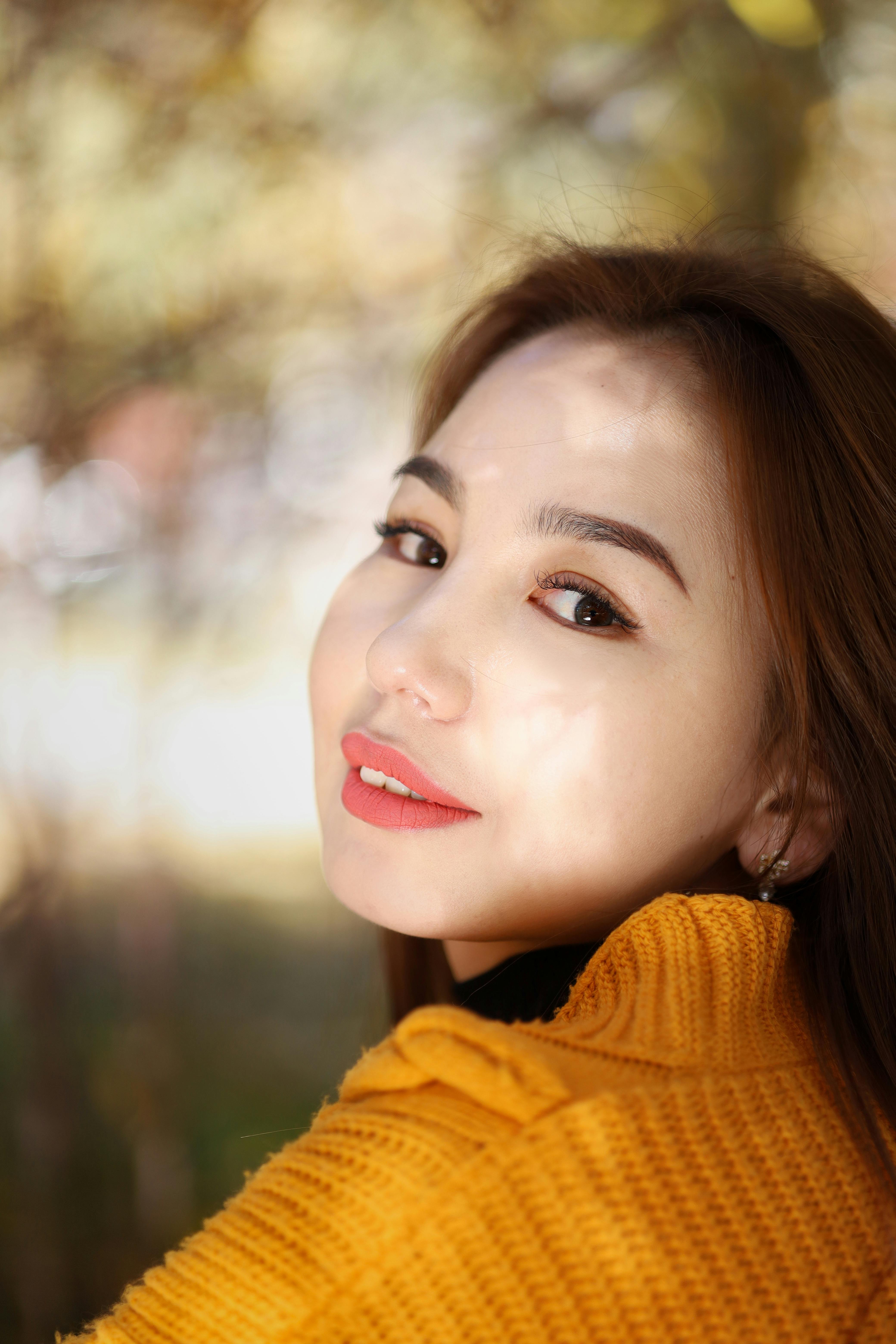 Elegant portrait of a smiling woman in a yellow sweater during a sunny autumn day.
