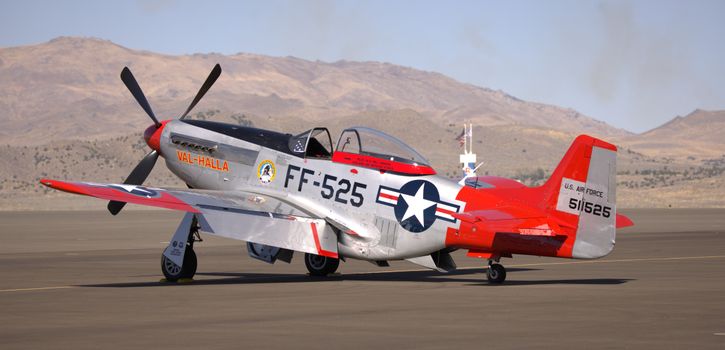 Classic P-51 Mustang airplane parked on runway, ready for takeoff.