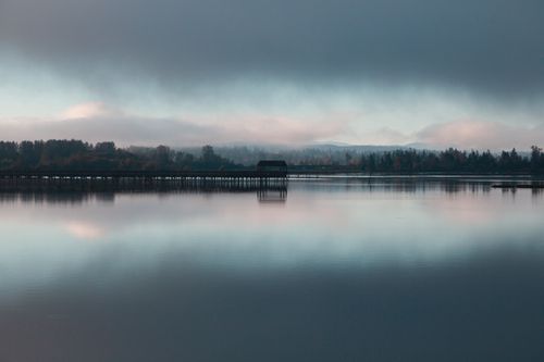 Free Peaceful autumn landscape with moody reflections on a calm lake under cloudy skies. Stock Photo