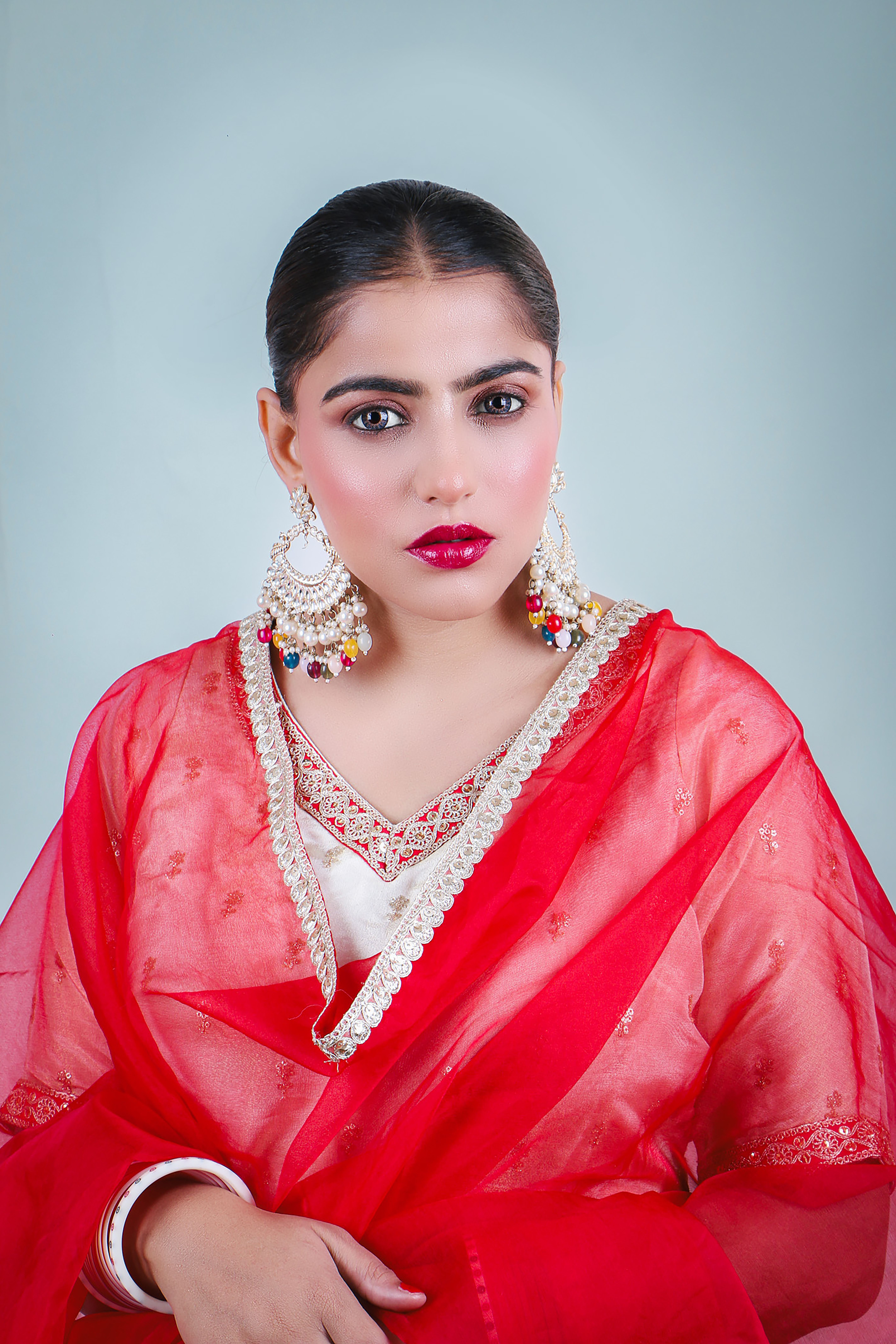 Striking portrait of a woman in red traditional Indian clothing, showcasing cultural elegance.