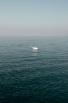 A serene view of a solitary boat on the calm sea near Cinqueterre, Italy.