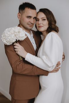 Charming couple in elegant attire, embracing with bouquet. Wedding theme.
