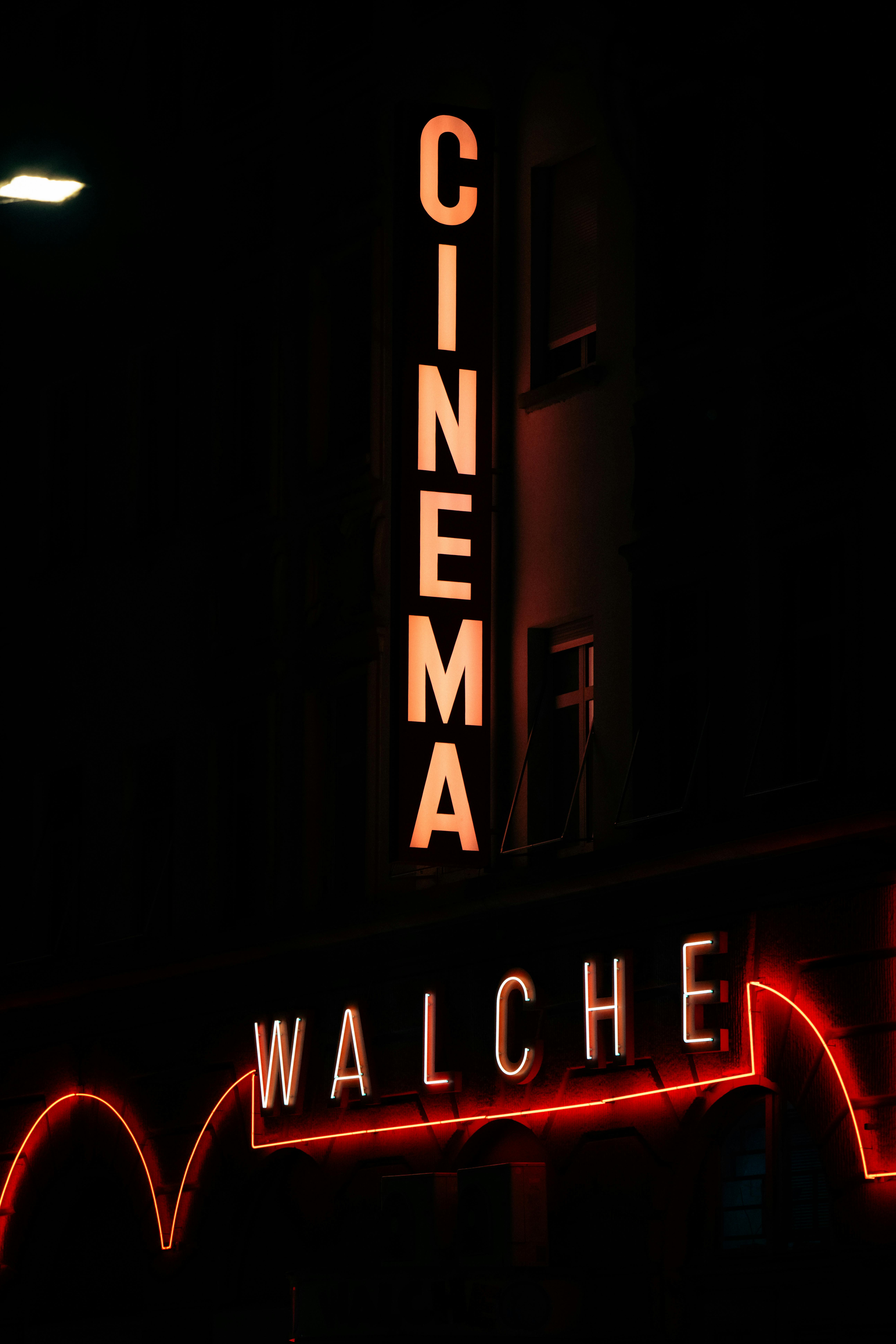 Gratuit Panneau de cinéma vintage éclairé au néon « Walche » brillant la nuit, évoquant l'ambiance d'un théâtre classique. Photos