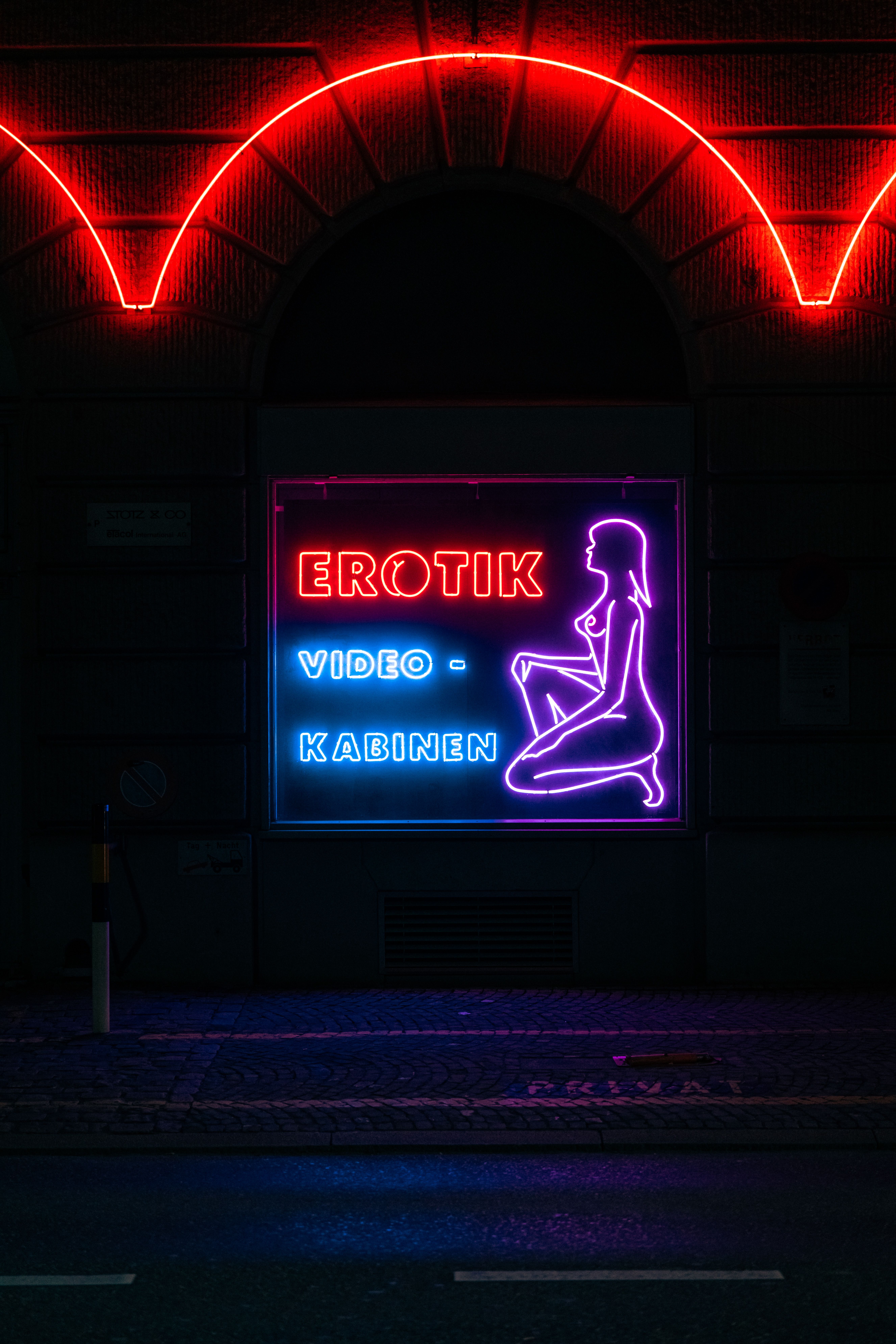 Vibrant neon sign displaying 'Erotik Video Kabinen' in nightlife setting. Captivating urban scene.