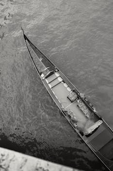 Black and white aerial view of a traditional Venetian gondola floating in the water in Venice, Italy.