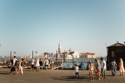 Tourists enjoy the sunny day by gondolas in Venice with a stunning view of the cityscape.