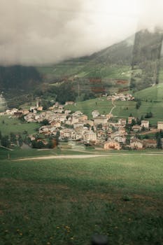 A picturesque view of Saint Moritz in Switzerland, surrounded by lush hills and clouds.
