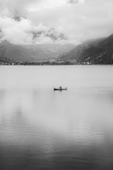 A lone boat on a tranquil Swiss lake with misty mountains in the background.