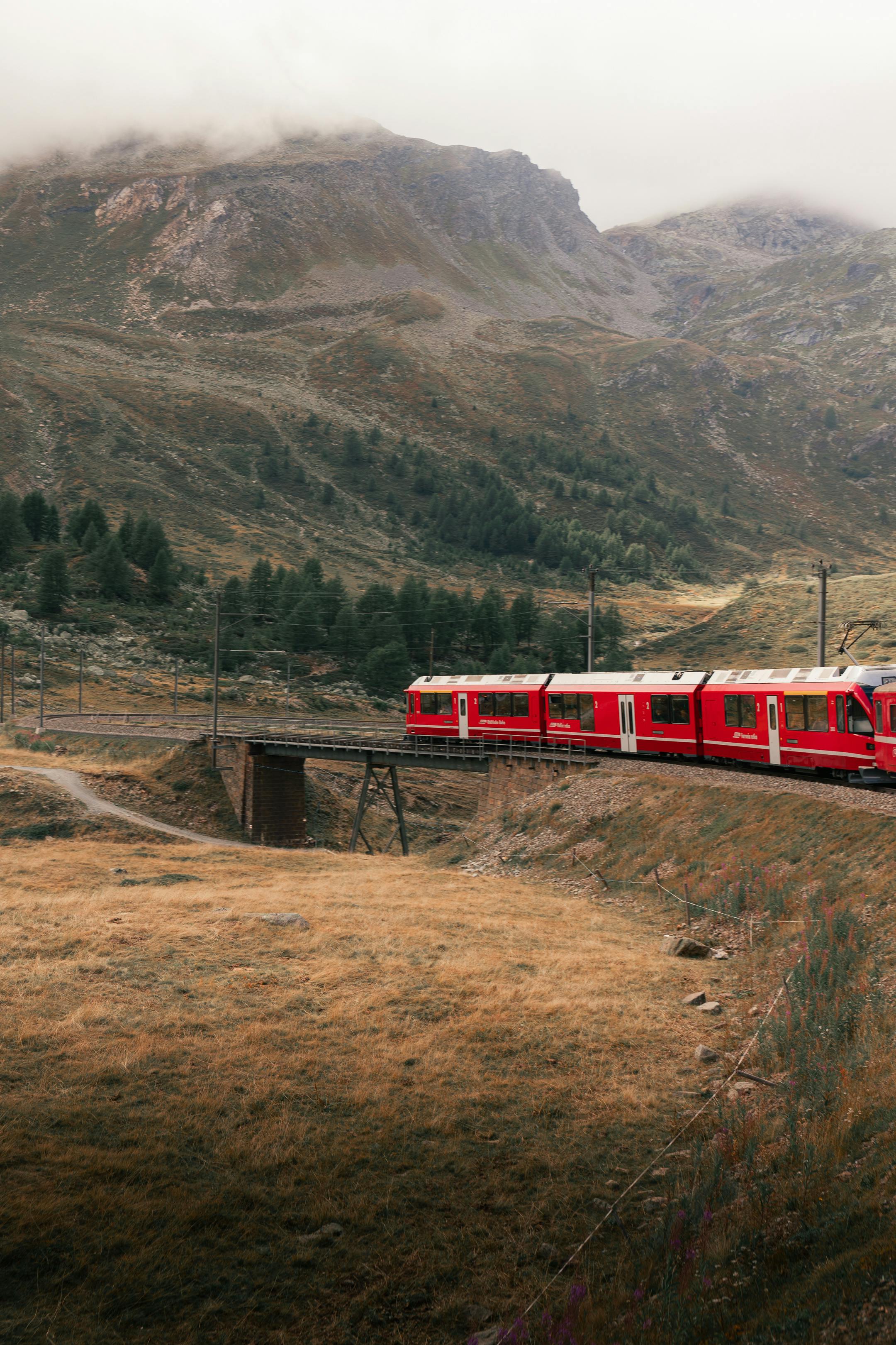Captivating view of a red train traversing the majestic Swiss Alps in autumn near Saint Moritz.