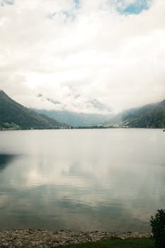 A tranquil lake surrounded by misty mountains in Saint Moritz, Switzerland.