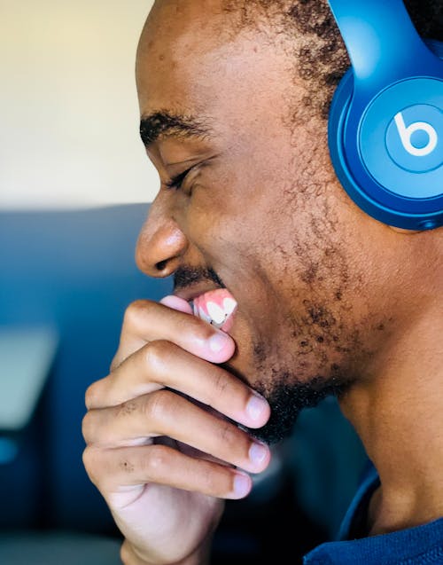 Ücretsiz Mavi Beats Kulaklık Kullanan Adam Gülümseyerek Stok Fotoğraflar