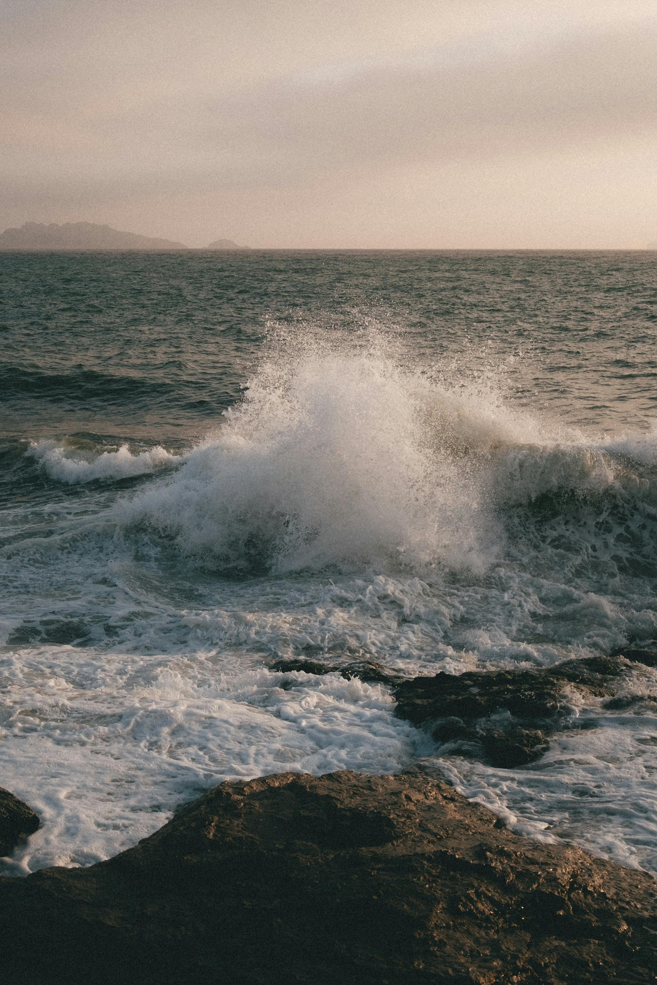 Dramatic ocean waves crashing on rocks at Marseille coastline during sunrise.