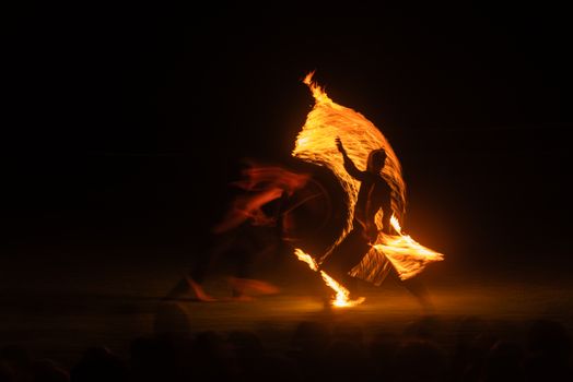 Captivating long-exposure shot of a fire performer creating trails of light against a dark backdrop.