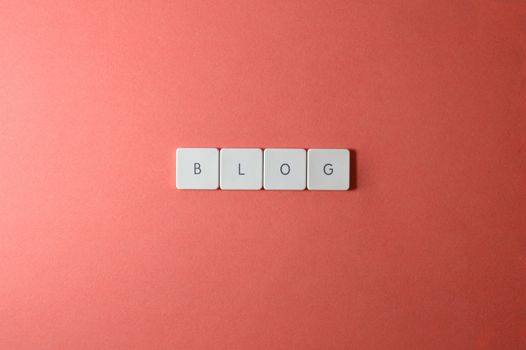A minimalist image of keyboard keys spelling 'BLOG' on a coral background.