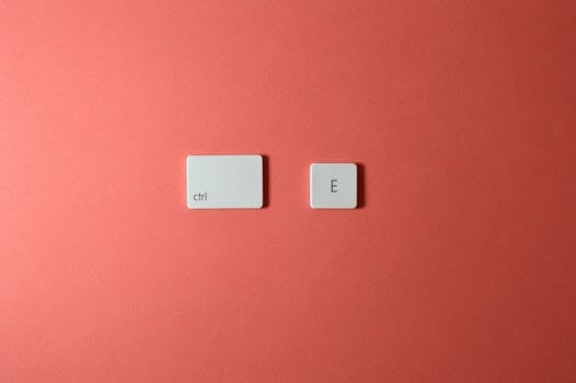 A minimalist arrangement of 'Ctrl' and 'E' keyboard keys on a coral background.