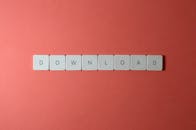 红色背景上，键盘瓷砖拼出“下载”的简约照片