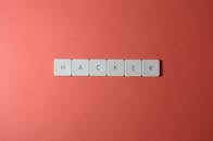 “黑客”一词的特写，由红色背景上的字母瓷砖制成，突出网络安全主题