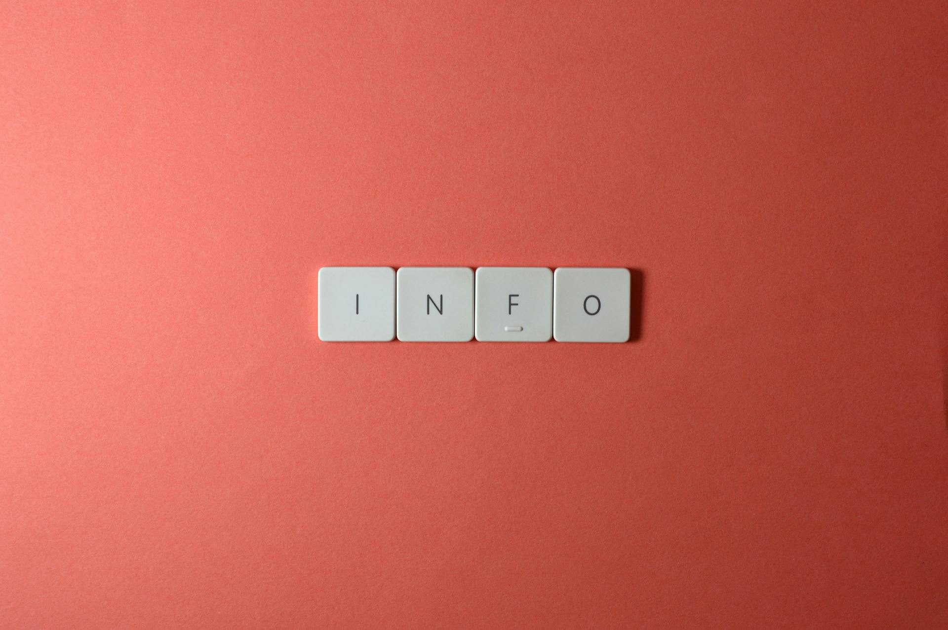 Close-up of keyboard buttons spelling 'INFO' on a minimal red background, ideal for tech and communication themes.