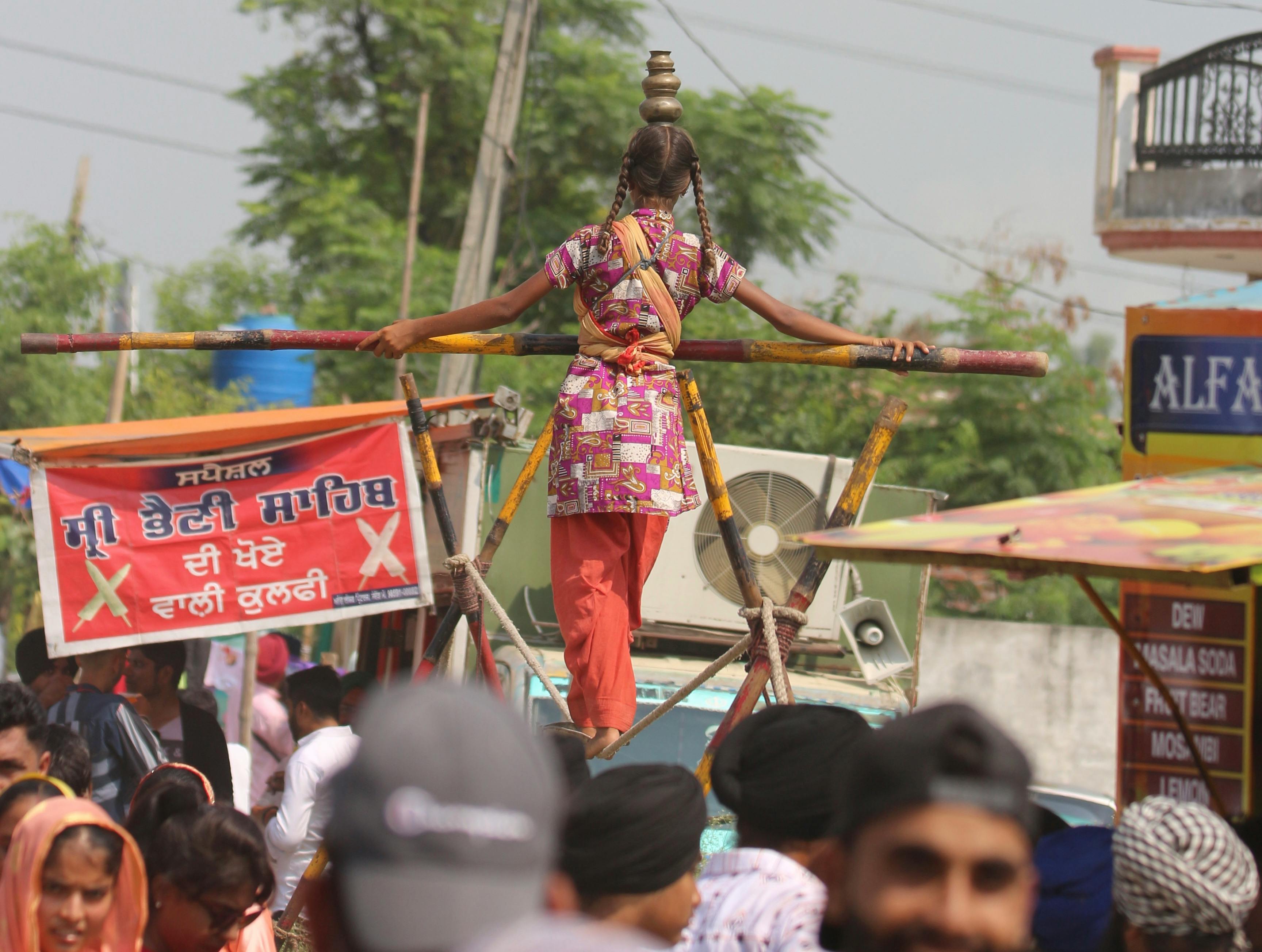 A young girl performs tightrope walking at a vibrant street festival.