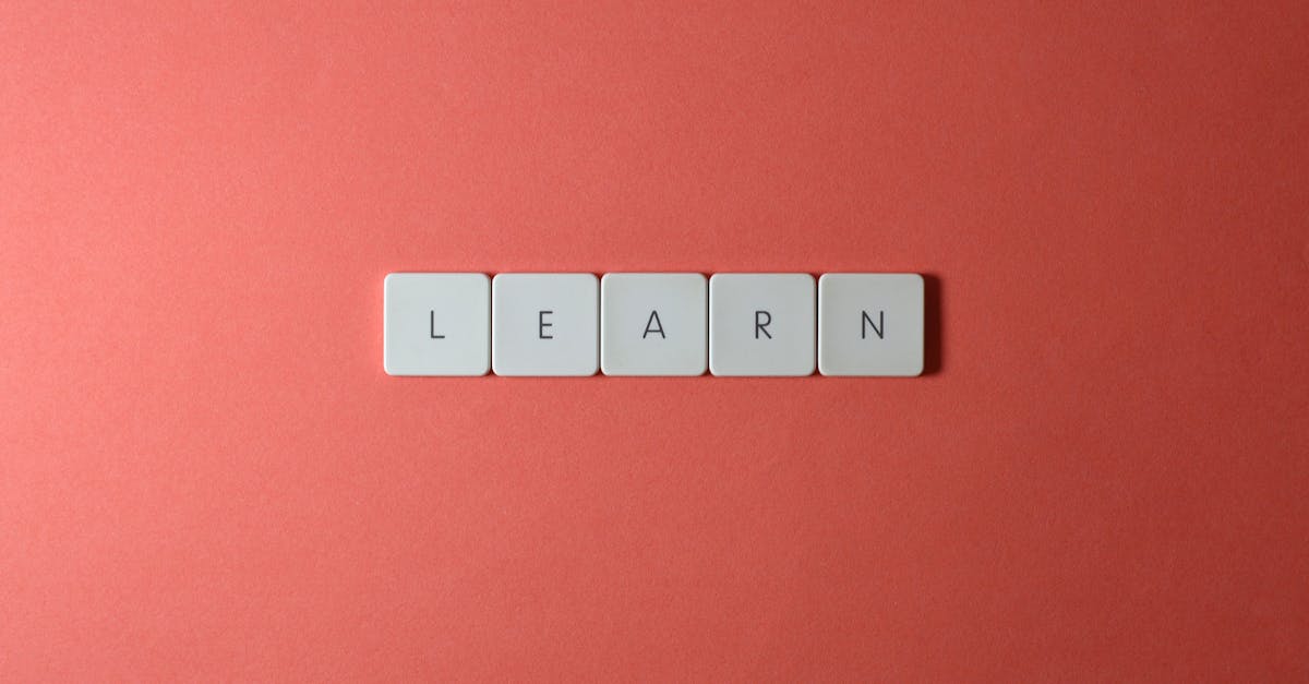Flat lay of word tiles spelling 'learn' on a coral background, symbolizing knowledge and education.