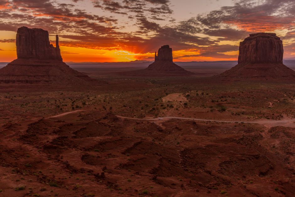 Capture the breathtaking view of Monument Valley's buttes at sunrise with dramatic skies and vibrant colors.
