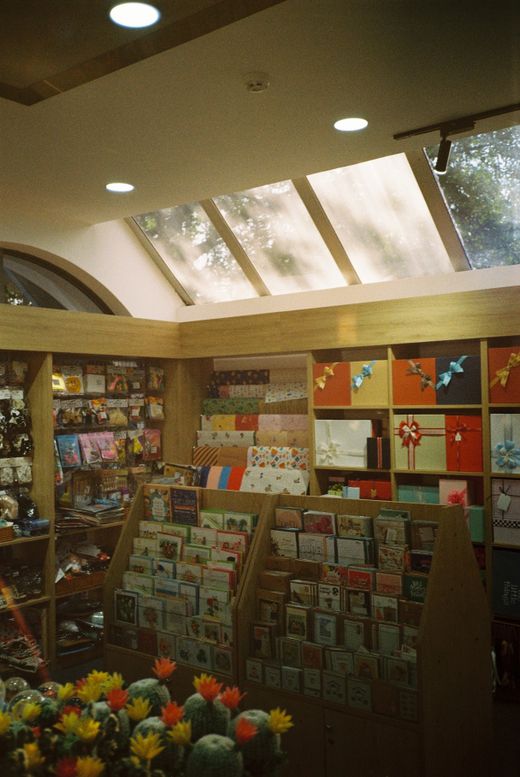 A sunlit stationery shop counter stacked with cards, notebooks and paper goods