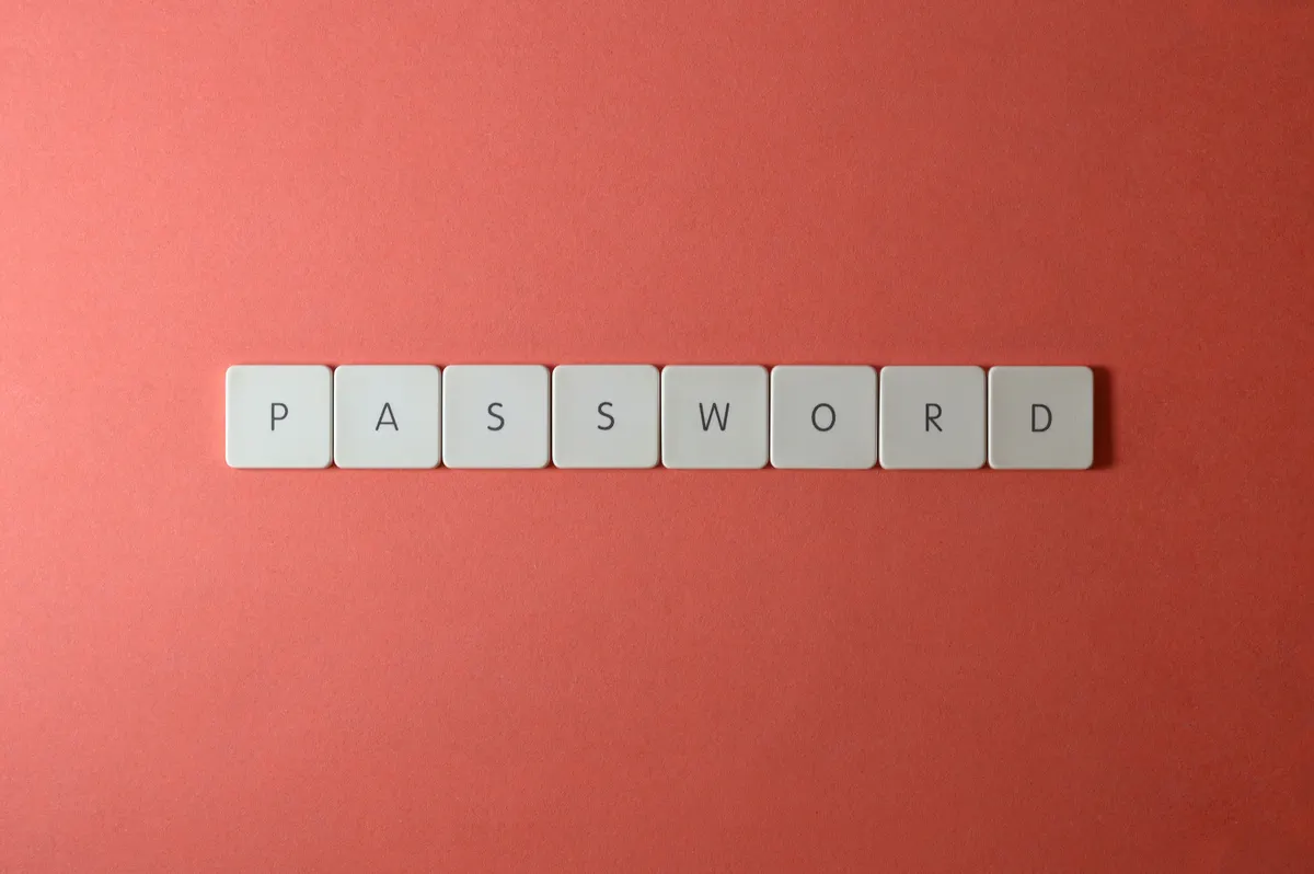 Keyboard letter tiles spelling out PASSWORD on a coral-colored background