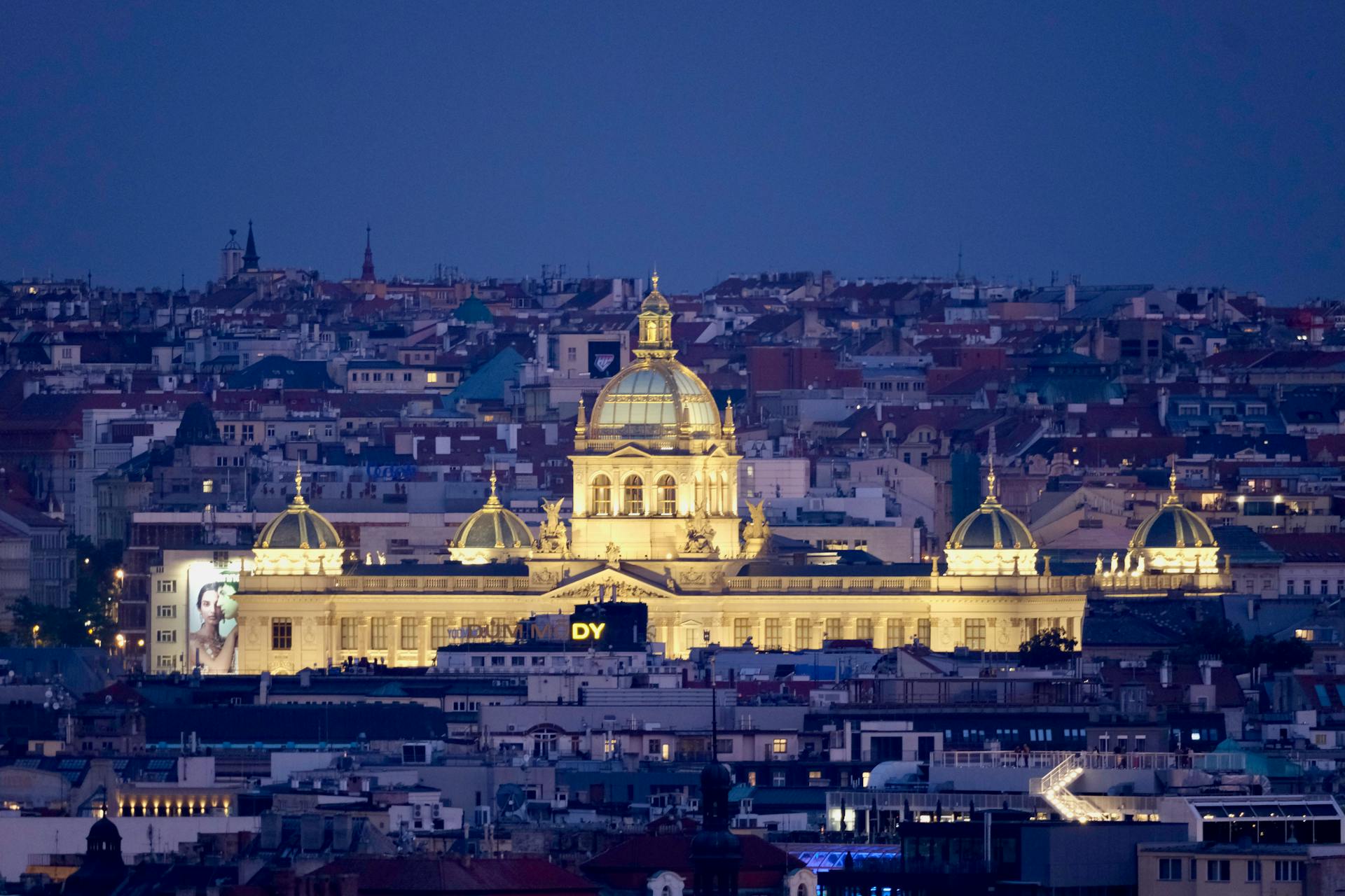 Evening view of the illuminated National Museum in Prague surrounded by a stunning cityscape.