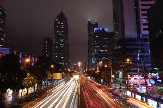 Bright city skyline at night with dynamic light trails on a busy street.