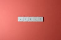 红色背景下特写拼写“病毒”的键盘键，非常适合概念用途