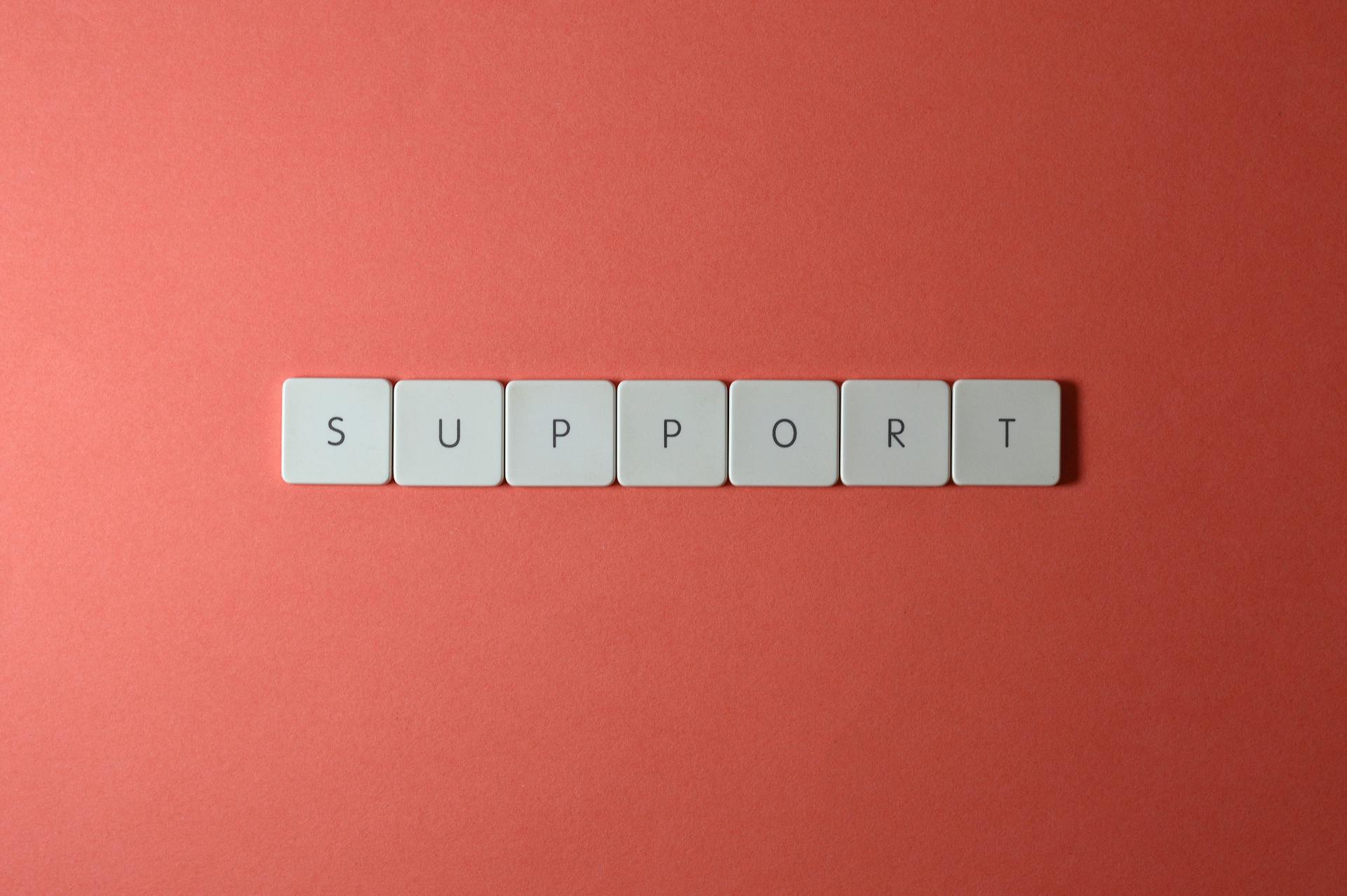 Close-up of the word 'support' spelled with keyboard keys on a red background.