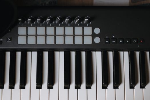 Close-up view of an electronic keyboard and control pad in a music studio.