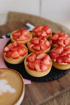 Fresh strawberry tarts on slate, paired with cappuccino.
